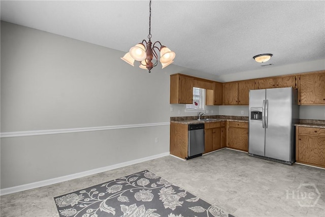 116 Gloucester Dr, Midway, GA 31320 - kitchen featuring stainless steel appliances, brown cabinetry, a chandelier, decorative light fixtures, and a textured ceiling