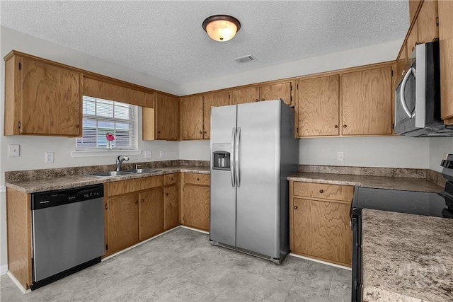 116 Gloucester Dr, Midway, GA 31320 - kitchen featuring appliances with stainless steel finishes, a textured ceiling, brown cabinetry, and dark countertops