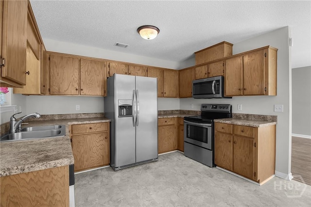116 Gloucester Dr, Midway, GA 31320 - kitchen featuring stainless steel appliances, brown cabinets, and a textured ceiling