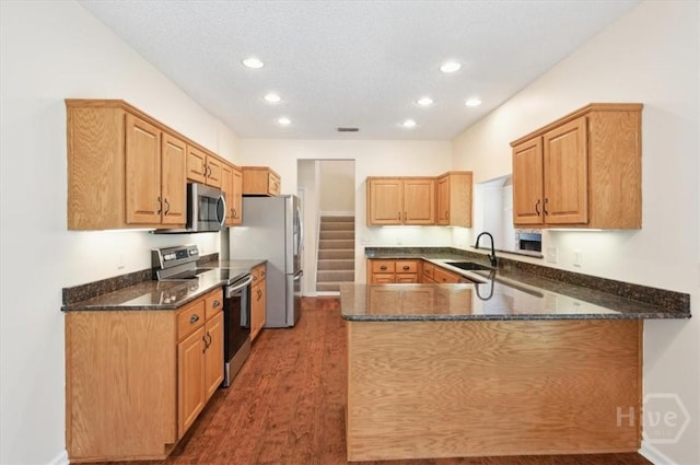 301 Marshview Dr, Richmond Hill, GA 31324 - kitchen featuring appliances with stainless steel finishes, wood finished floors, dark stone counters, a peninsula, and recessed lighting