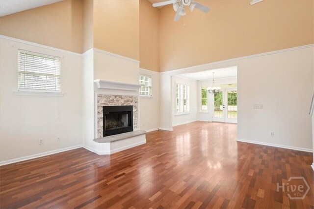 301 Marshview Dr, Richmond Hill, GA 31324 - unfurnished living room featuring a towering ceiling, ceiling fan, a fireplace, wood finished floors, and a chandelier
