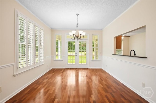 301 Marshview Dr, Richmond Hill, GA 31324 - unfurnished dining area with a chandelier, ornamental molding, wood finished floors, french doors, and a textured ceiling
