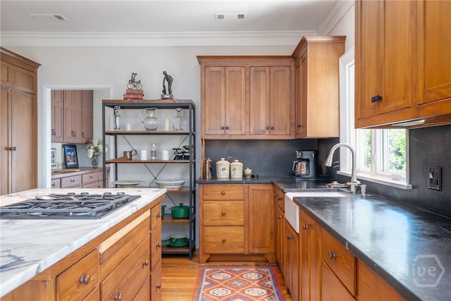 3 She Crab Cir, Savannah, GA 31411 - kitchen with stainless steel gas cooktop, open shelves, brown cabinets, light wood-type flooring, and backsplash