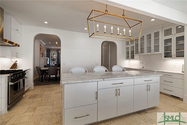 52-56 E Broad St, Savannah, GA 31401 - kitchen featuring high end stainless steel range oven, arched walkways, stone tile floors, wall chimney range hood, and recessed lighting