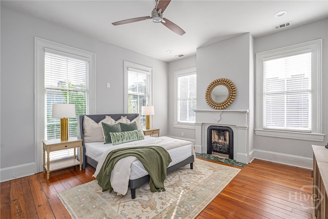121 W Bolton St, Savannah, GA 31401 - bedroom featuring hardwood / wood-style flooring, multiple windows, a fireplace with flush hearth, and a ceiling fan