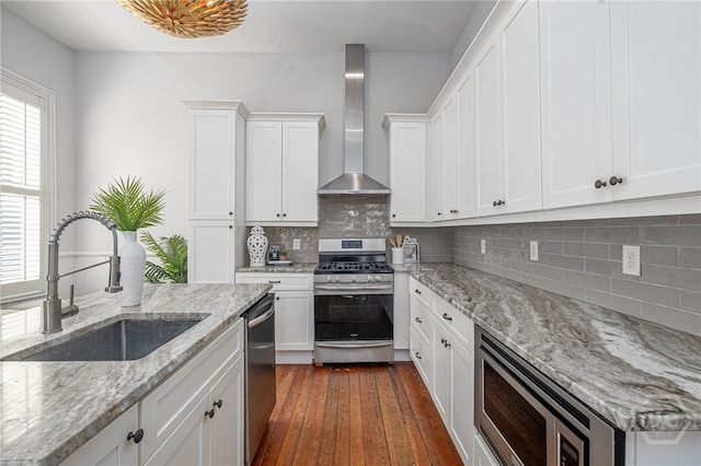 121 W Bolton St, Savannah, GA 31401 - kitchen featuring stainless steel appliances, wall chimney exhaust hood, white cabinets, and backsplash