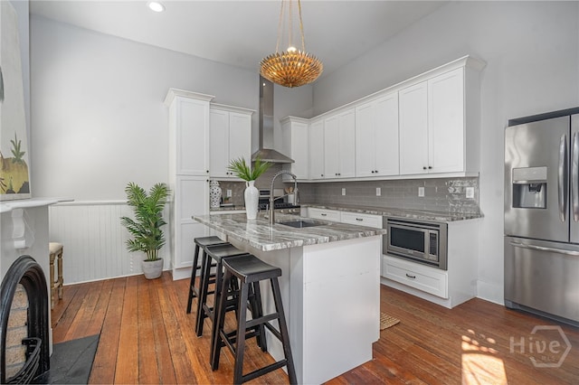 121 W Bolton St, Savannah, GA 31401 - kitchen with appliances with stainless steel finishes, wall chimney exhaust hood, dark wood finished floors, light stone countertops, and a wainscoted wall