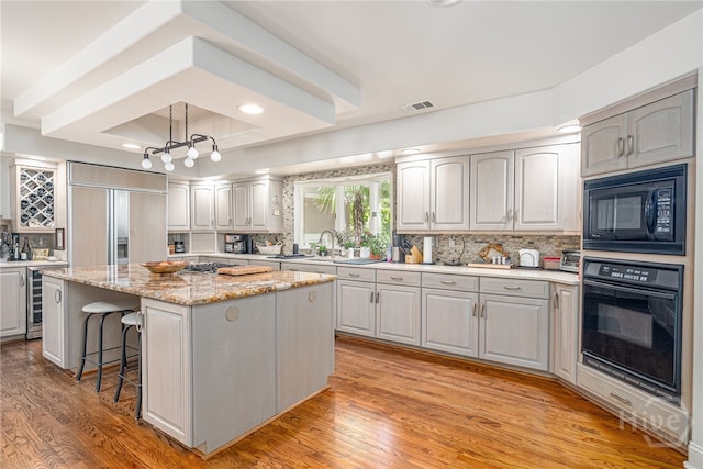32 Hasleiters Retreat Retreat, Savannah, GA 31411 - kitchen with black appliances, beverage cooler, a center island, decorative backsplash, and light wood-style floors