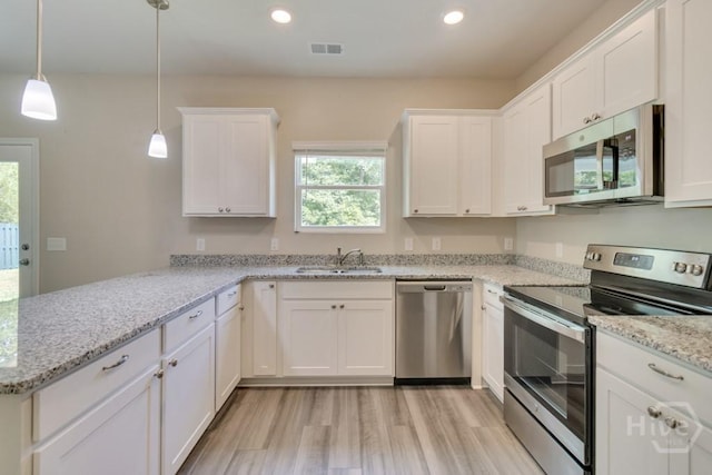 1057 Waybridge Way, Richmond Hill, GA 31324 - kitchen with stainless steel appliances, a peninsula, light wood finished floors, white cabinetry, and recessed lighting
