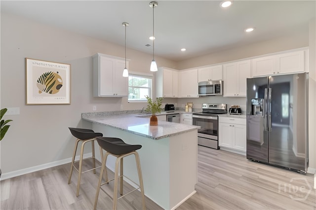 1057 Waybridge Way, Richmond Hill, GA 31324 - kitchen with appliances with stainless steel finishes, a peninsula, white cabinetry, light wood-style flooring, and pendant lighting