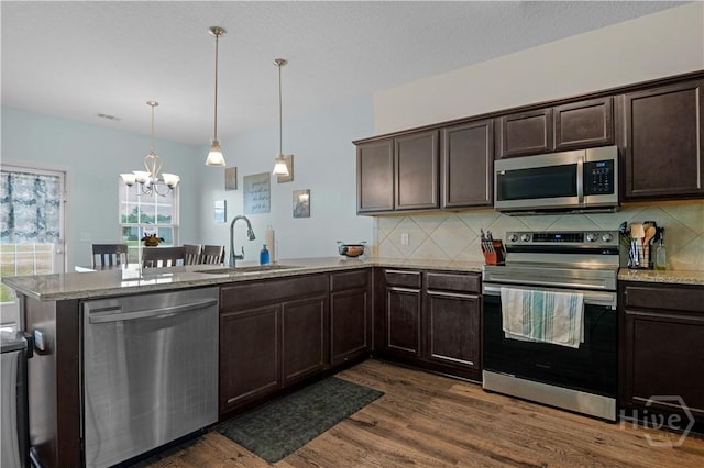 291 Morgan Field Blvd NE, Ludowici, GA 31316 - kitchen with appliances with stainless steel finishes, a peninsula, dark brown cabinetry, dark wood finished floors, and a chandelier