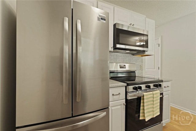 127 Laurel Green Ct, Savannah, GA 31419 - kitchen featuring appliances with stainless steel finishes, backsplash, white cabinetry, light wood-type flooring, and a textured ceiling