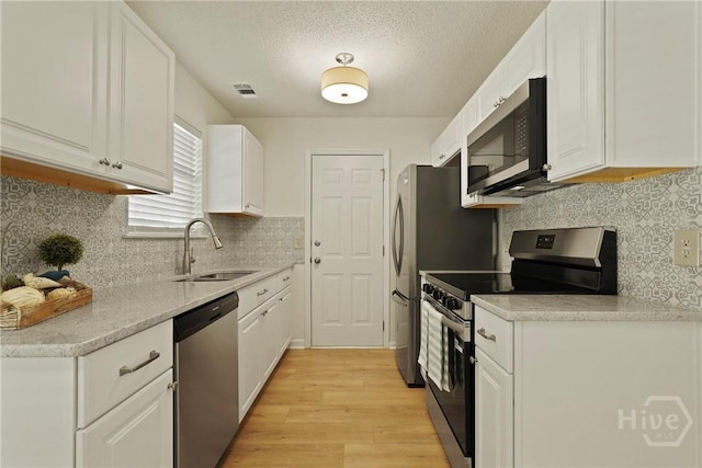 127 Laurel Green Ct, Savannah, GA 31419 - kitchen featuring appliances with stainless steel finishes, light wood-style floors, white cabinetry, decorative backsplash, and light countertops