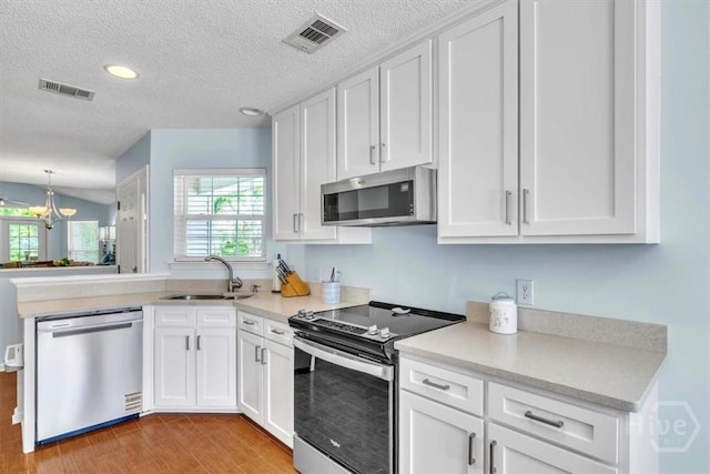 24 Marsh Hen Ct, Richmond Hill, GA 31324 - kitchen featuring stainless steel appliances, white cabinetry, light countertops, a textured ceiling, and a peninsula