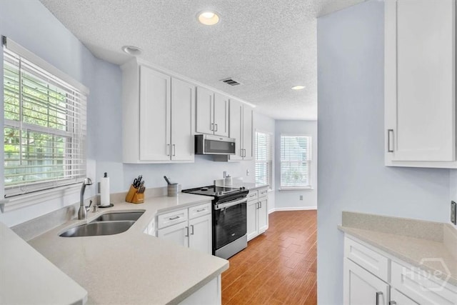24 Marsh Hen Ct, Richmond Hill, GA 31324 - kitchen with stainless steel appliances, a textured ceiling, light countertops, white cabinets, and light wood-style flooring