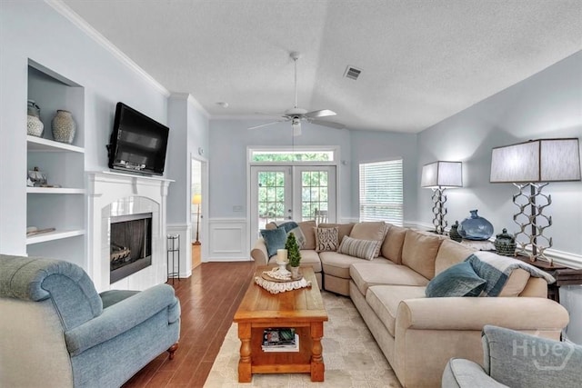 24 Marsh Hen Ct, Richmond Hill, GA 31324 - living area with wood finished floors, ceiling fan, vaulted ceiling, a fireplace, and a wainscoted wall