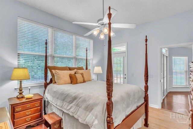 24 Marsh Hen Ct, Richmond Hill, GA 31324 - bedroom with light wood-style floors, access to exterior, a ceiling fan, and a textured ceiling