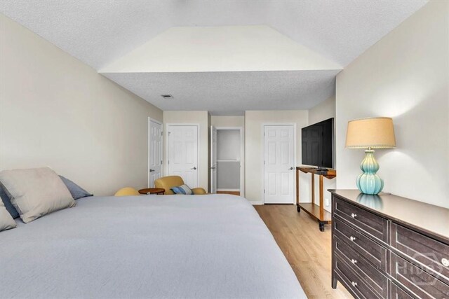 24 Marsh Hen Ct, Richmond Hill, GA 31324 - bedroom with light wood-type flooring, lofted ceiling, and a textured ceiling
