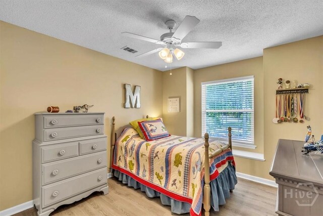 24 Marsh Hen Ct, Richmond Hill, GA 31324 - bedroom with light wood finished floors, a textured ceiling, and a ceiling fan