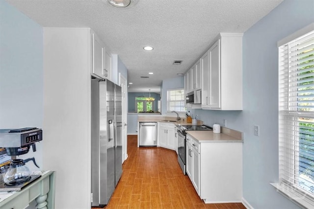 24 Marsh Hen Ct, Richmond Hill, GA 31324 - kitchen with stainless steel appliances, light countertops, white cabinetry, a textured ceiling, and recessed lighting