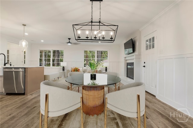 103 Kentshire Ct, Savannah, GA 31410 - dining room with a decorative wall, crown molding, a glass covered fireplace, a chandelier, and wood finished floors