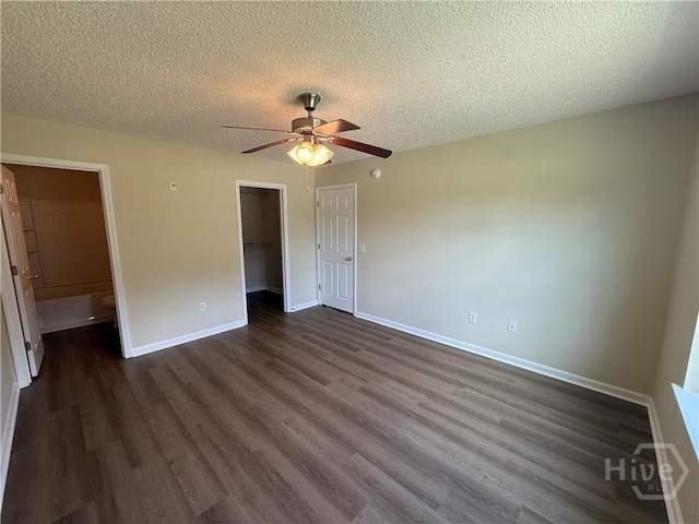 150 Knotty Pine Cir, Springfield, GA 31329 - unfurnished bedroom with dark wood-style floors, a textured ceiling, a closet, a walk in closet, and a ceiling fan