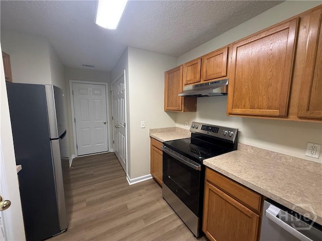 150 Knotty Pine Cir, Springfield, GA 31329 - kitchen with appliances with stainless steel finishes, under cabinet range hood, light wood-style floors, light countertops, and a textured ceiling