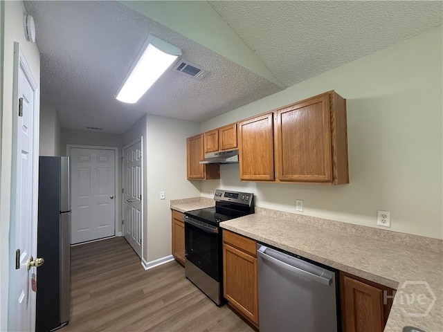 150 Knotty Pine Cir, Springfield, GA 31329 - kitchen featuring stainless steel appliances, under cabinet range hood, light wood-style flooring, a textured ceiling, and light countertops