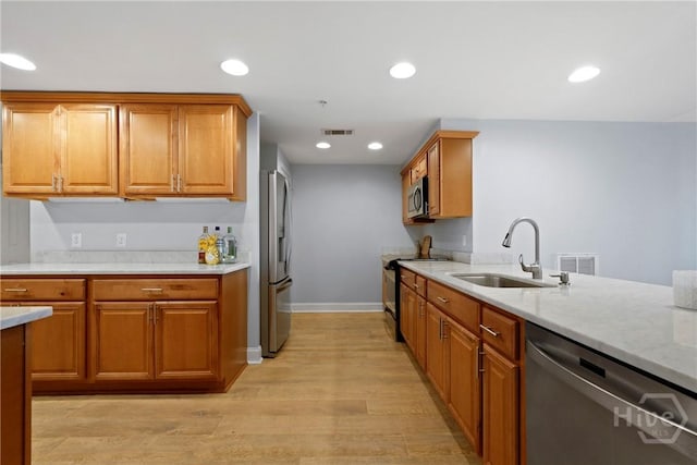 3113 River Dr Unit 10, Savannah, GA 31404 - kitchen with stainless steel appliances, light wood-style flooring, brown cabinetry, recessed lighting, and light stone countertops