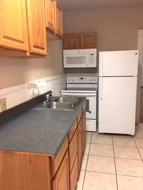 908-910 E 34th St, Savannah, GA 31401 - kitchen with white appliances, dark countertops, light tile patterned floors, and wainscoting