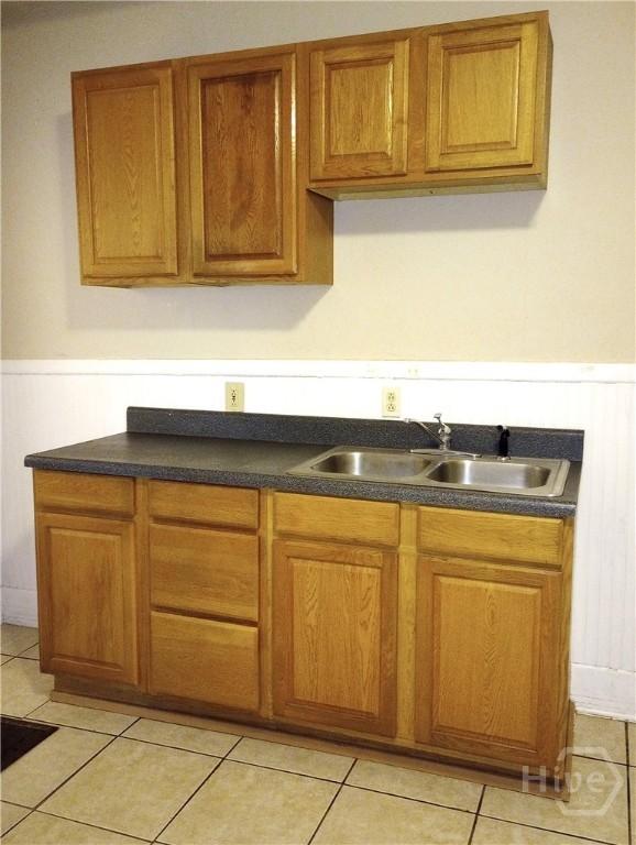 908-910 E 34th St, Savannah, GA 31401 - kitchen with wainscoting, dark countertops, brown cabinetry, and light tile patterned flooring