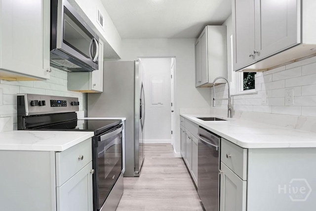 2204 Beaumont Dr, Savannah, GA 31406 - kitchen with appliances with stainless steel finishes, light wood-type flooring, decorative backsplash, and gray cabinetry