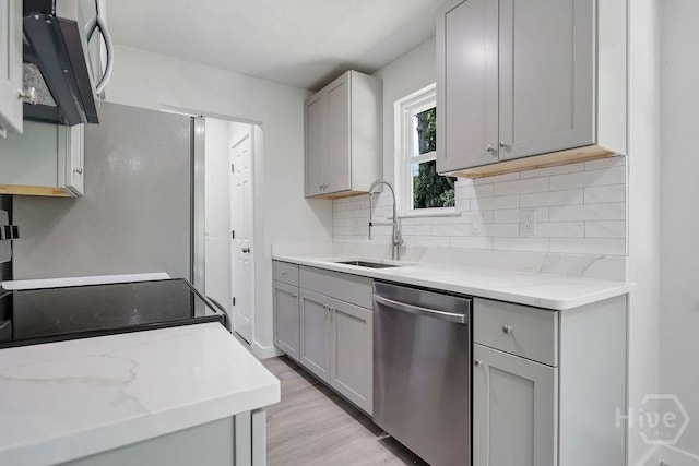 2204 Beaumont Dr, Savannah, GA 31406 - kitchen with stainless steel dishwasher, gray cabinets, backsplash, light wood-type flooring, and light stone countertops