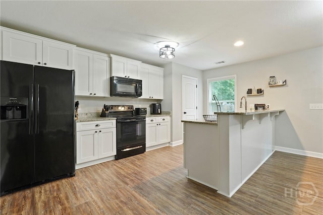 1175 Ralph Rahn Rd, Rincon, GA 31326 - kitchen featuring black appliances, a peninsula, white cabinetry, wood finished floors, and recessed lighting