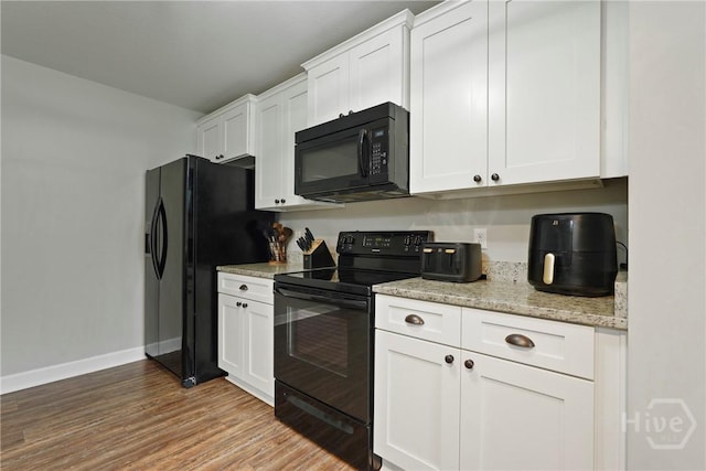1175 Ralph Rahn Rd, Rincon, GA 31326 - kitchen featuring black appliances, white cabinetry, light wood finished floors, and light stone countertops