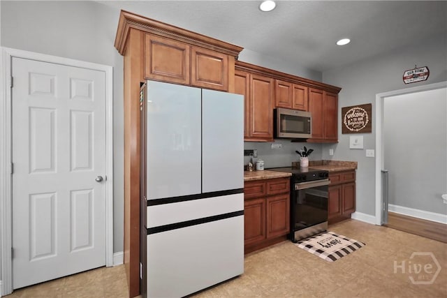 43 Gracie Ln NE, Ludowici, GA 31316 - kitchen with freestanding refrigerator, stainless steel microwave, black / electric stove, brown cabinets, and recessed lighting