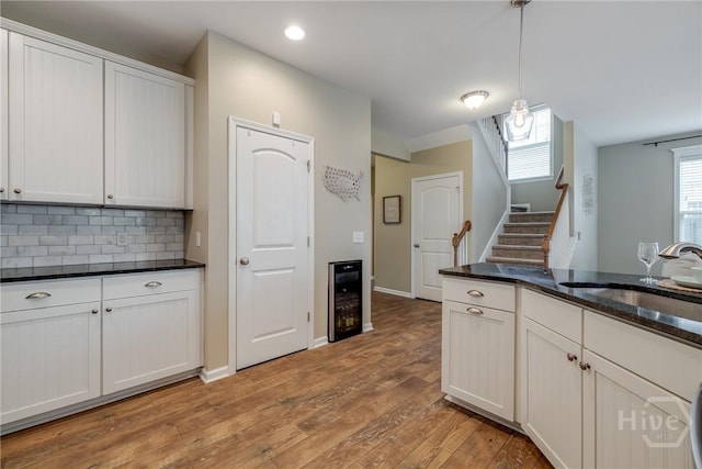 55 Glen Way, Richmond Hill, GA 31324 - kitchen with wine cooler, light wood-style floors, hanging light fixtures, tasteful backsplash, and dark stone countertops