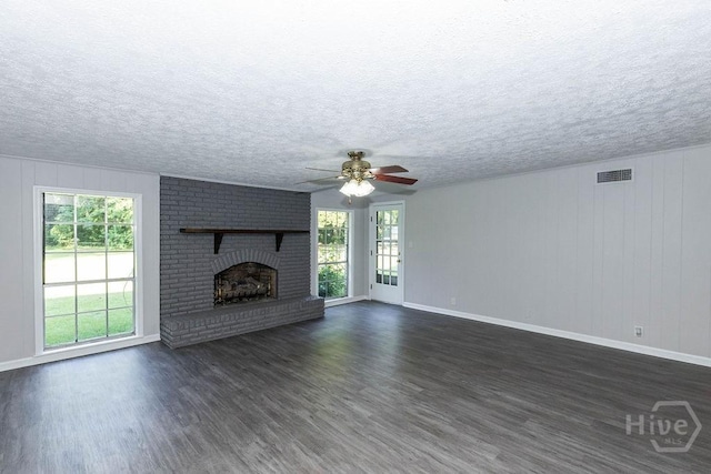 84 Poplar St, Guyton, GA 31312 - unfurnished living room featuring plenty of natural light, dark wood-style flooring, a ceiling fan, a brick fireplace, and a textured ceiling