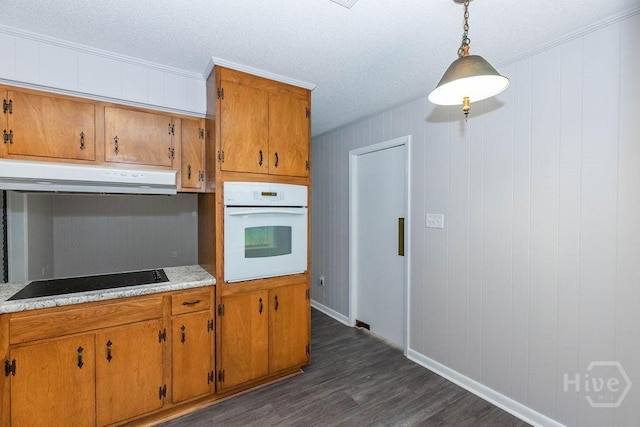 84 Poplar St, Guyton, GA 31312 - kitchen with white oven, under cabinet range hood, black electric cooktop, dark wood finished floors, and brown cabinets