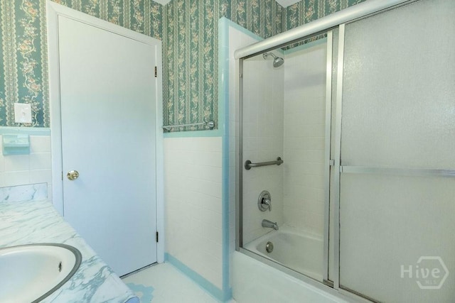 84 Poplar St, Guyton, GA 31312 - bathroom featuring wallpapered walls, a wainscoted wall, bath / shower combo with glass door, vanity, and tile walls