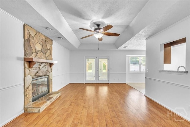 237 Robinson Loop, Richmond Hill, GA 31324 - unfurnished living room featuring a tray ceiling, french doors, ceiling fan, a textured ceiling, and light wood-style floors