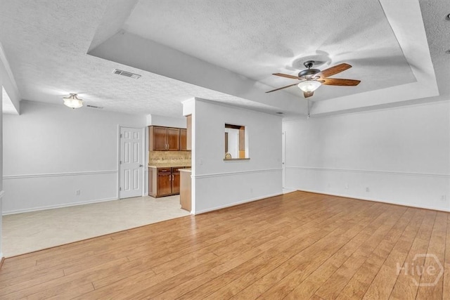 237 Robinson Loop, Richmond Hill, GA 31324 - unfurnished living room with a textured ceiling, a tray ceiling, light wood-style flooring, and ceiling fan