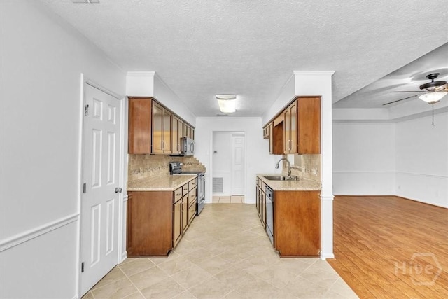 237 Robinson Loop, Richmond Hill, GA 31324 - kitchen with appliances with stainless steel finishes, a ceiling fan, tasteful backsplash, brown cabinets, and a textured ceiling
