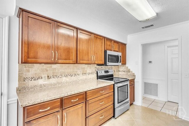 237 Robinson Loop, Richmond Hill, GA 31324 - kitchen featuring stainless steel appliances, brown cabinetry, light tile patterned floors, tasteful backsplash, and light stone counters