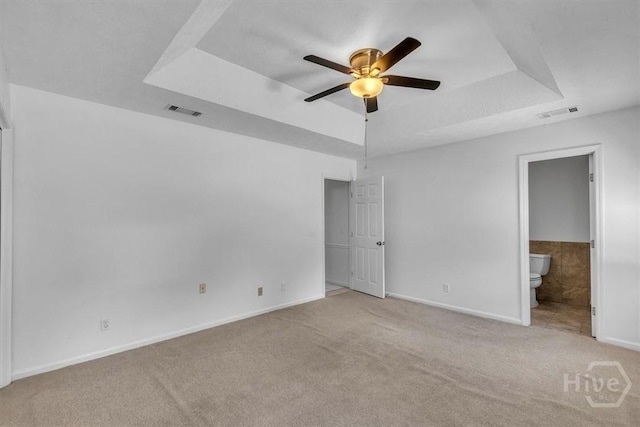 237 Robinson Loop, Richmond Hill, GA 31324 - unfurnished bedroom featuring a tray ceiling, carpet floors, connected bathroom, and a ceiling fan