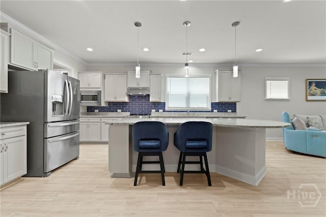 137 Harvest Hl, Pooler, GA 31322 - kitchen with appliances with stainless steel finishes, tasteful backsplash, a breakfast bar, a kitchen island, and under cabinet range hood