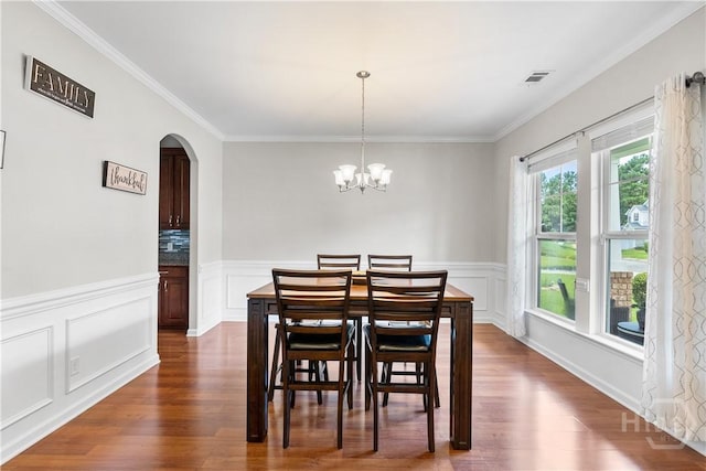 9 Melody Dr, Pooler, GA 31322 - dining space featuring arched walkways, dark wood-type flooring, crown molding, wainscoting, and a chandelier