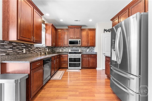 9 Melody Dr, Pooler, GA 31322 - kitchen with appliances with stainless steel finishes, light wood-type flooring, tasteful backsplash, recessed lighting, and dark stone counters