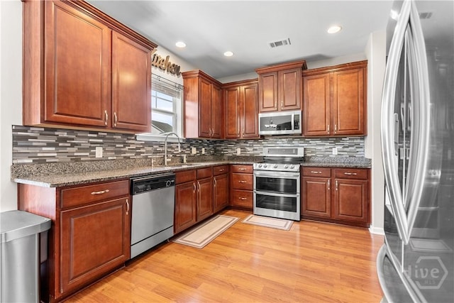 9 Melody Dr, Pooler, GA 31322 - kitchen featuring stainless steel appliances, light wood finished floors, decorative backsplash, brown cabinetry, and recessed lighting