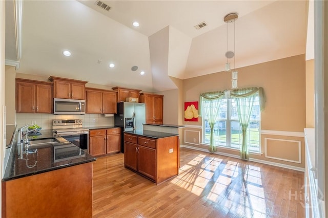 9 Sweetwater Ct, Savannah, GA 31419 - kitchen featuring appliances with stainless steel finishes, brown cabinets, light wood-type flooring, a center island, and a decorative wall